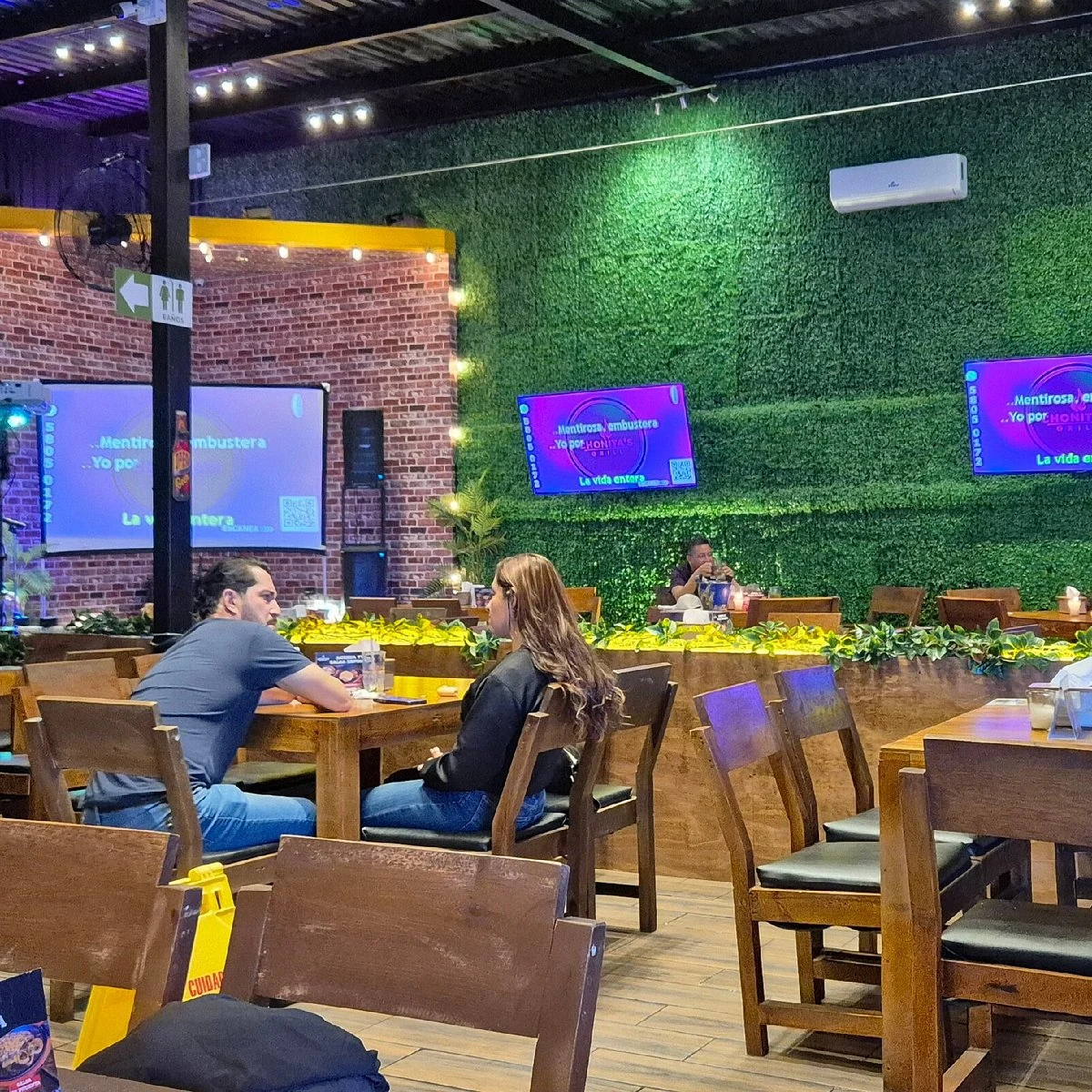 Interior de Chonita's Grill con mesas, pantallas y ambiente nocturno